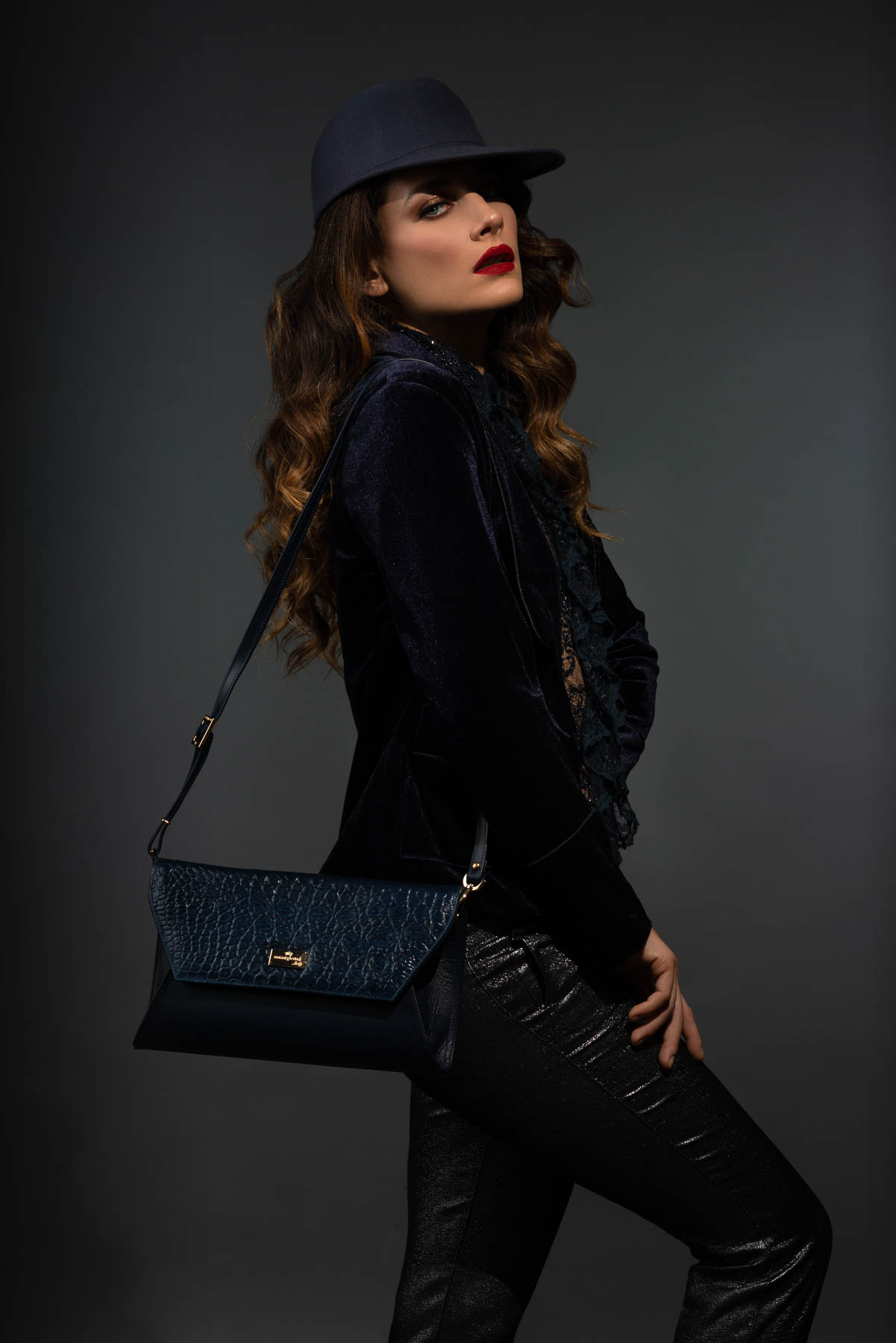 Modella in posa su sfondo scuro in studio fotografico per pubblicità di borse da donna
