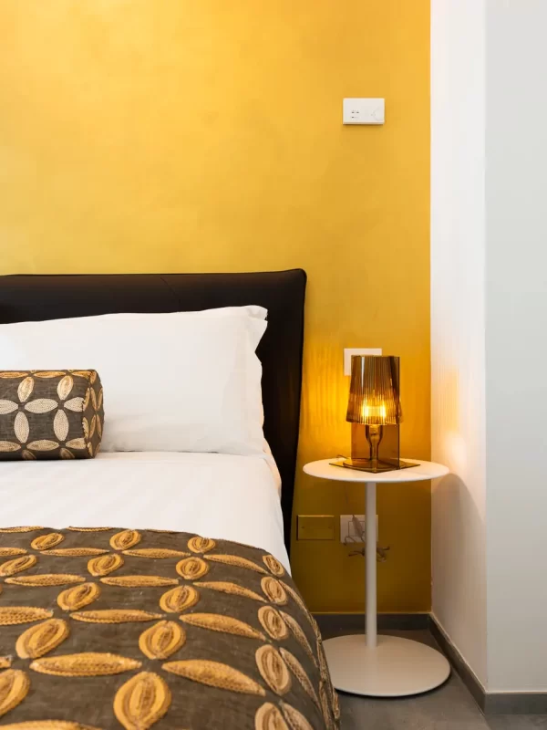 Dettaglio di letto e comodino di una camera del Karma Resort di San Benedetto del Tronto