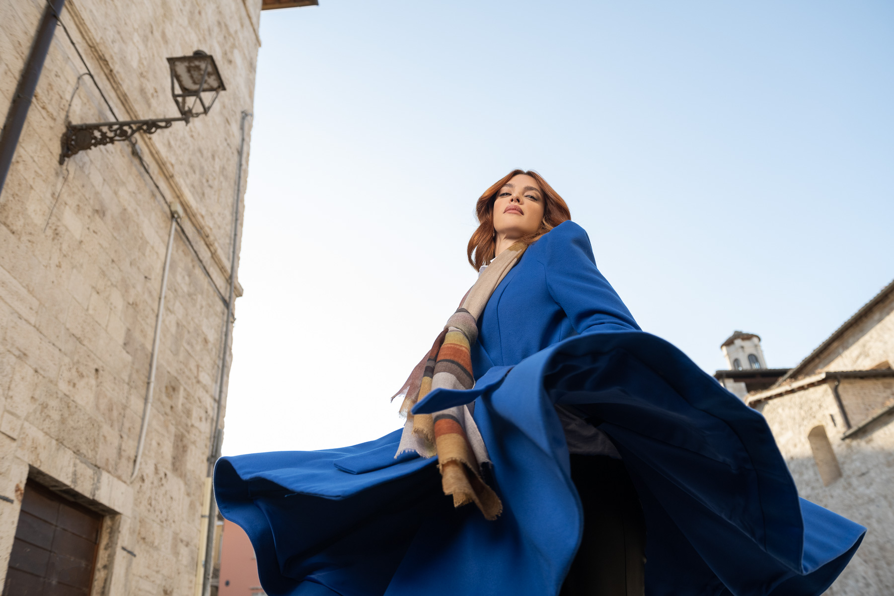 Modella con cappotto blu e sciarpa, posa per un servizio di moda ad Ascoli Piceno